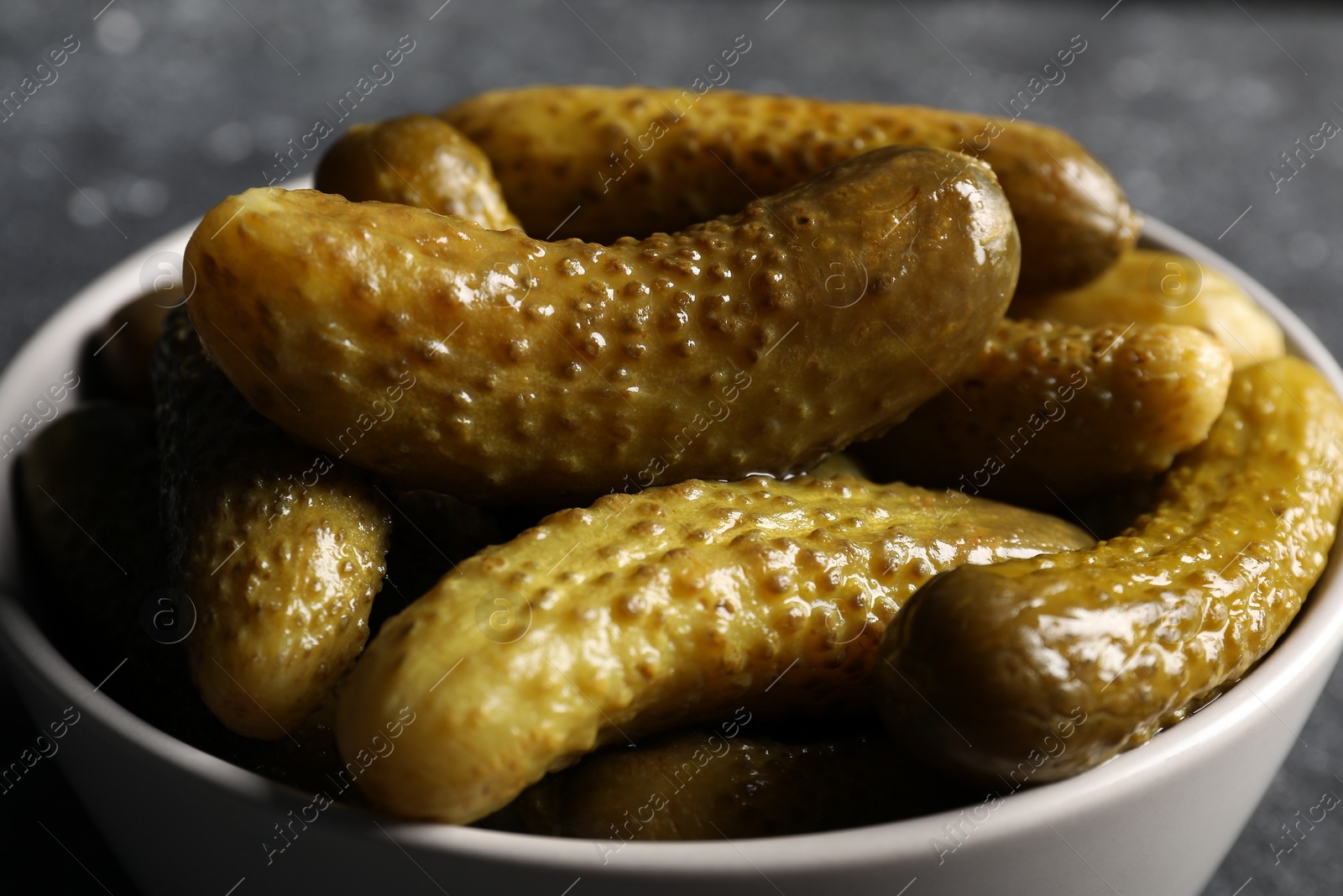 Photo of Tasty pickled cucumbers in bowl on table, closeup