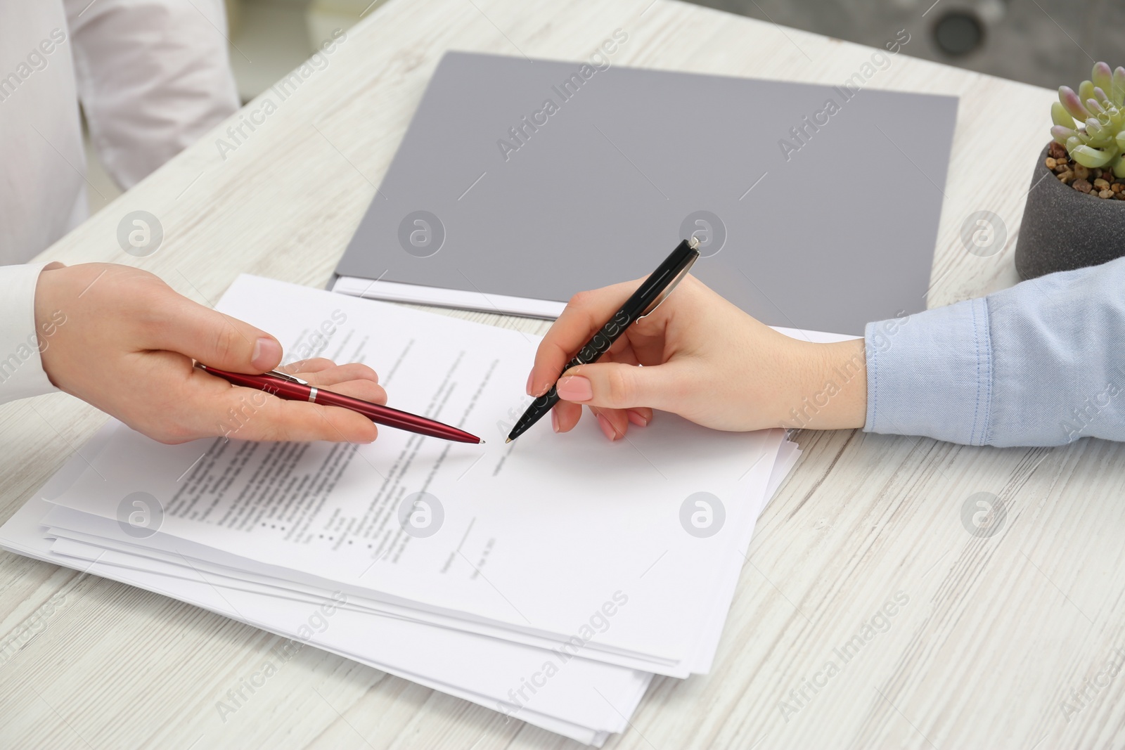 Photo of Man signing document at wooden table, closeup