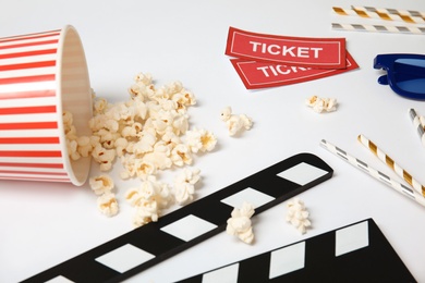 Photo of Clapper, popcorn and tickets on white background. Cinema snack