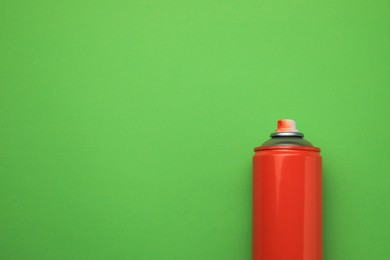 Photo of Can of red graffiti spray paint on green background, top view. Space for text