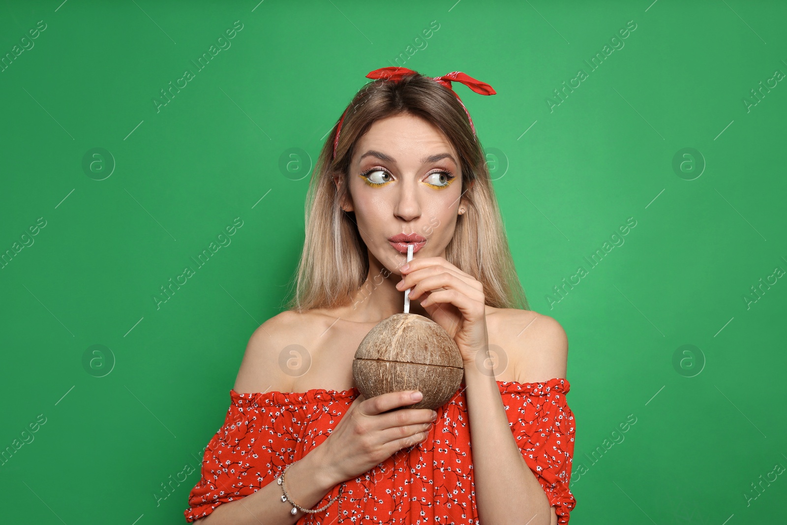 Photo of Young woman with fresh coconut on green background. Exotic fruit