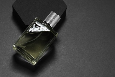 Photo of Stylish presentation of luxury men`s perfume in bottle on black background, space for text