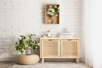 Photo of Beautiful jasmine flowers and wooden commode in room