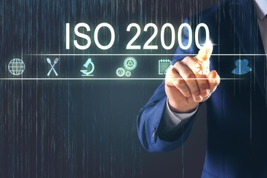 Image of Man pointing at virtual screen with text ISO 22000 and different icons, closeup