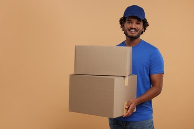 Photo of Happy courier with parcels on light brown background, space for text