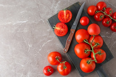 Photo of Flat lay composition with fresh whole and cut tomatoes on grey marble table. Space for text