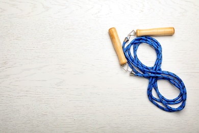 Photo of Jump rope and space for text on white wooden background, top view