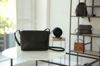 Photo of Stylish woman's bag on stand in boutique. Space for text
