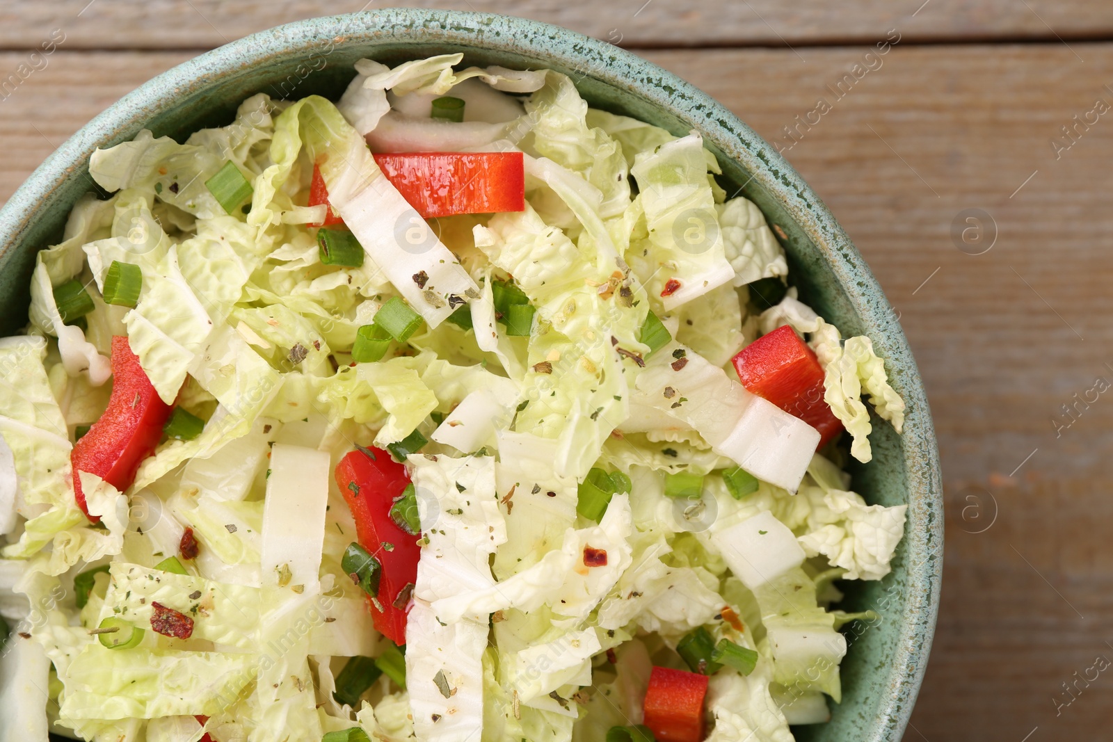 Photo of Tasty salad with Chinese cabbage, bell pepper and green onion in bowl on wooden table, top view