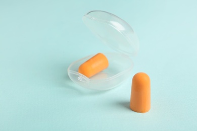 Photo of Pair of orange ear plugs and case on turquoise background