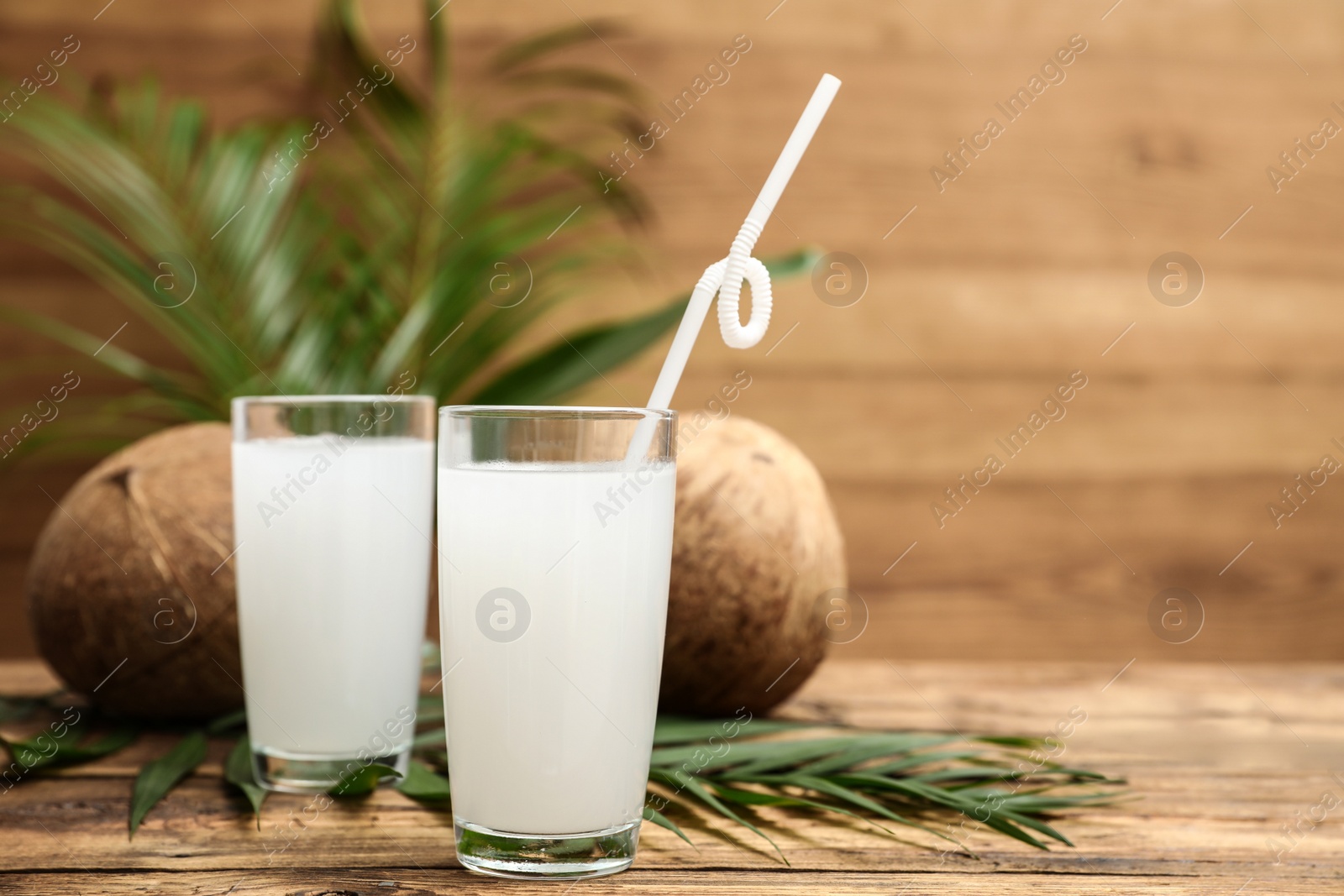 Photo of Composition with glasses of coconut water on wooden background. Space for text