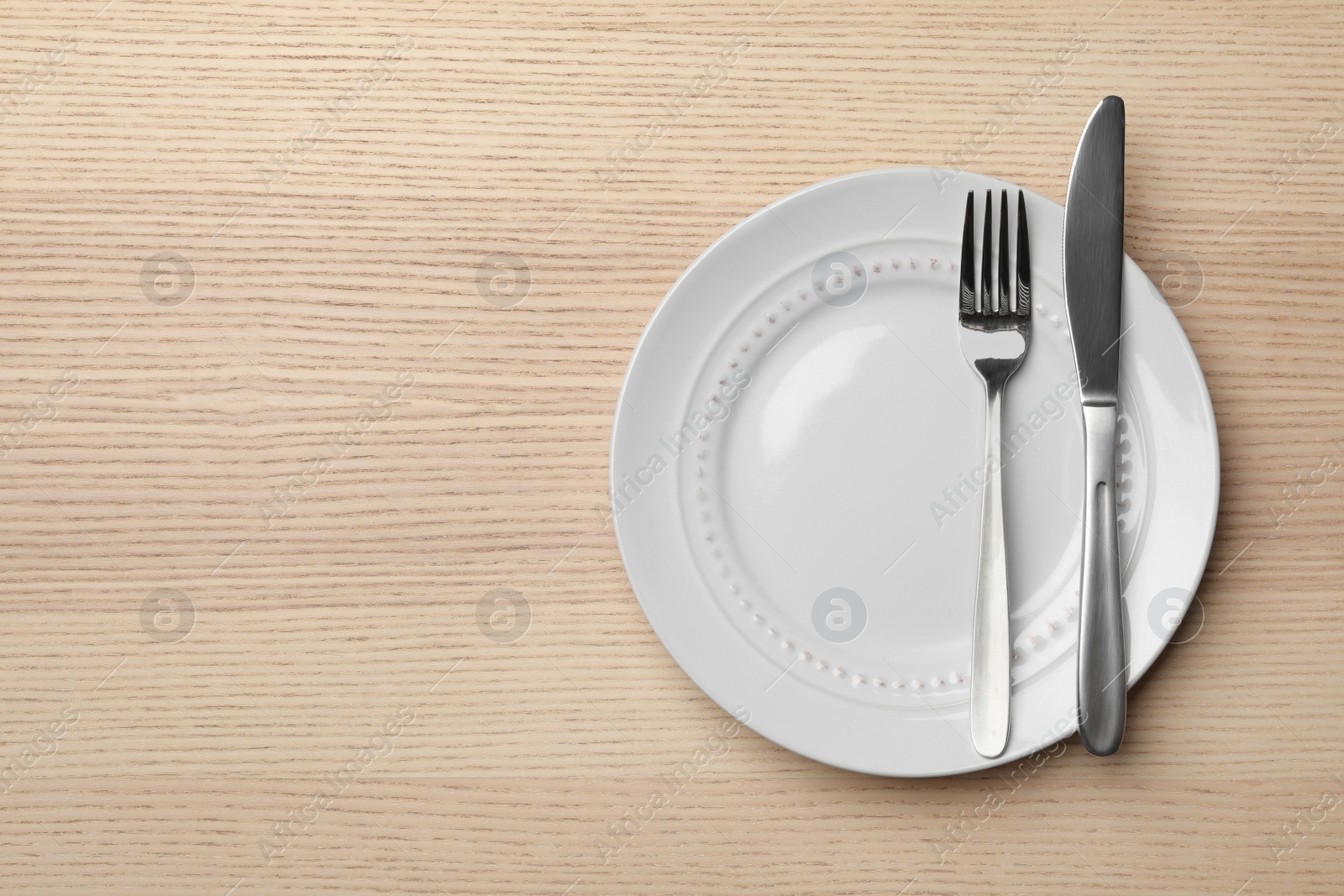 Photo of Stylish ceramic plate and cutlery on wooden background, flat lay. Space for text