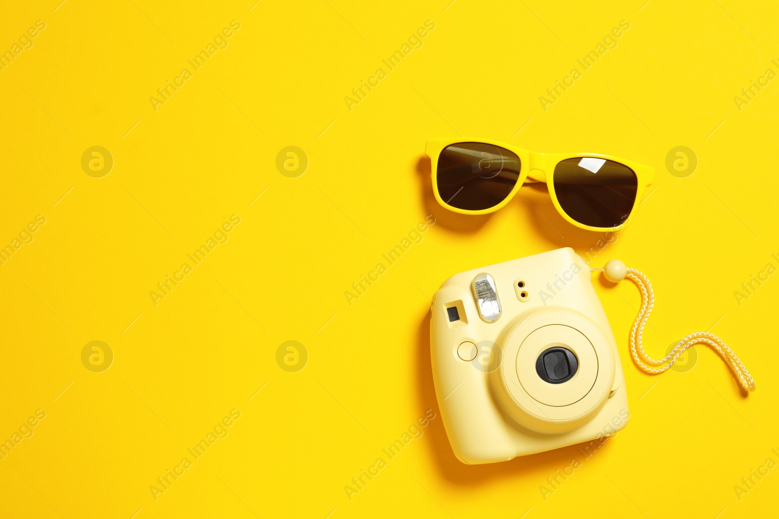 Photo of Sunglasses and camera on color background, top view with space for text. Beach accessories