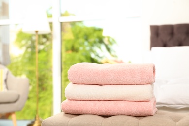 Photo of Stack of soft clean terry towels on bedside bench. Space for text