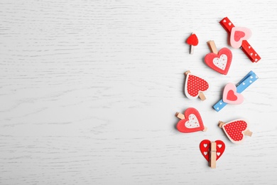 Photo of Decorative pegs with hearts on wooden background, top view. Space for text