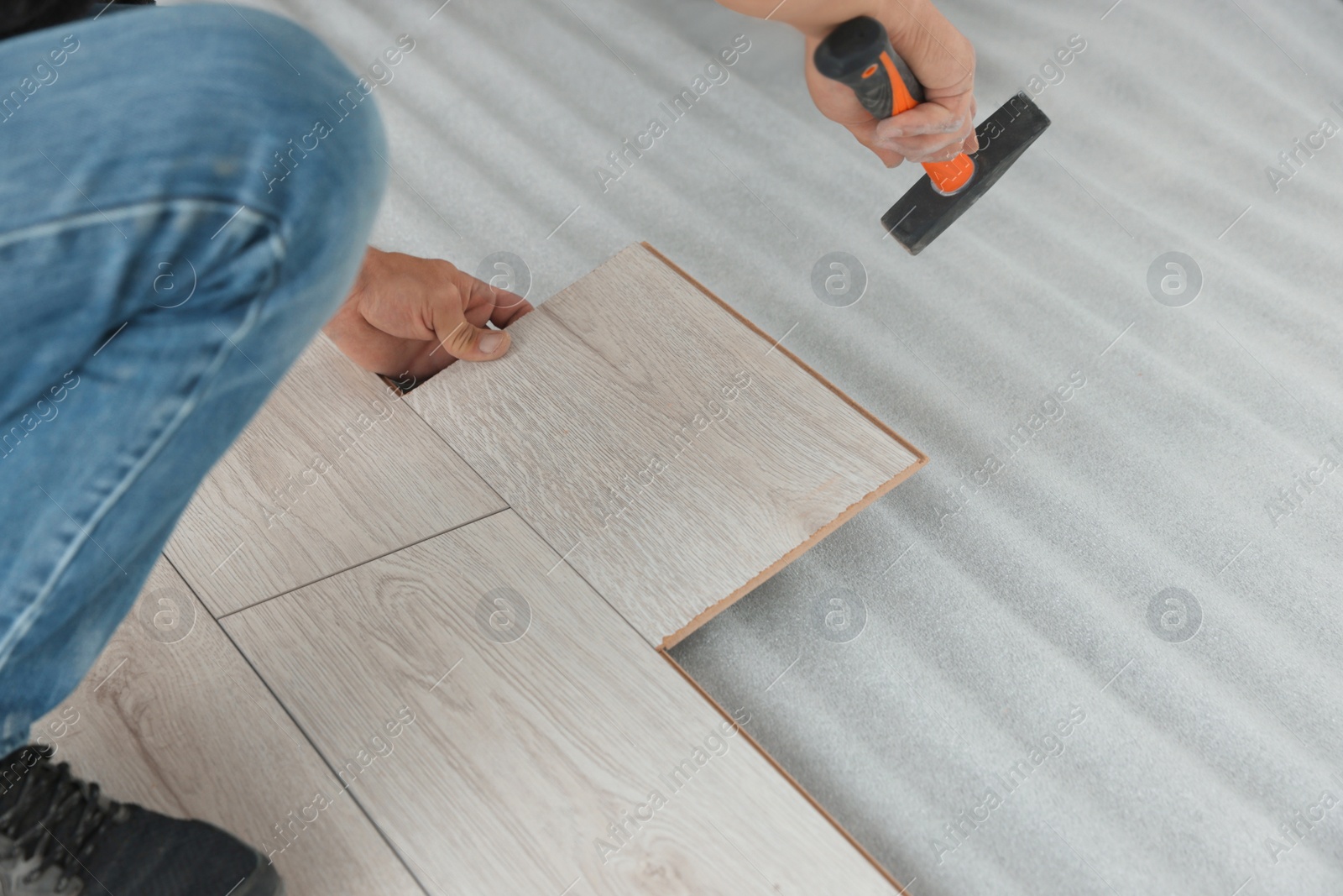 Photo of Worker installing new laminate flooring in room, closeup