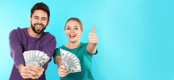Image of Happy young couple with money on turquoise background, space for text. Banner design