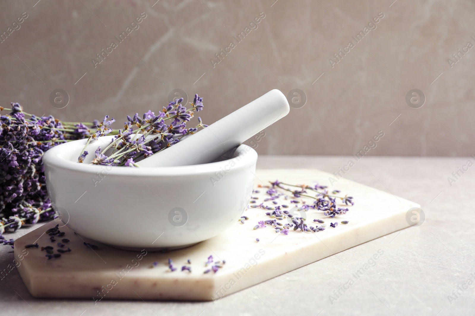 Photo of Mortar and pestle with lavender flowers on grey stone background, space for text. Natural cosmetic