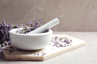 Photo of Mortar and pestle with lavender flowers on grey stone background, space for text. Natural cosmetic