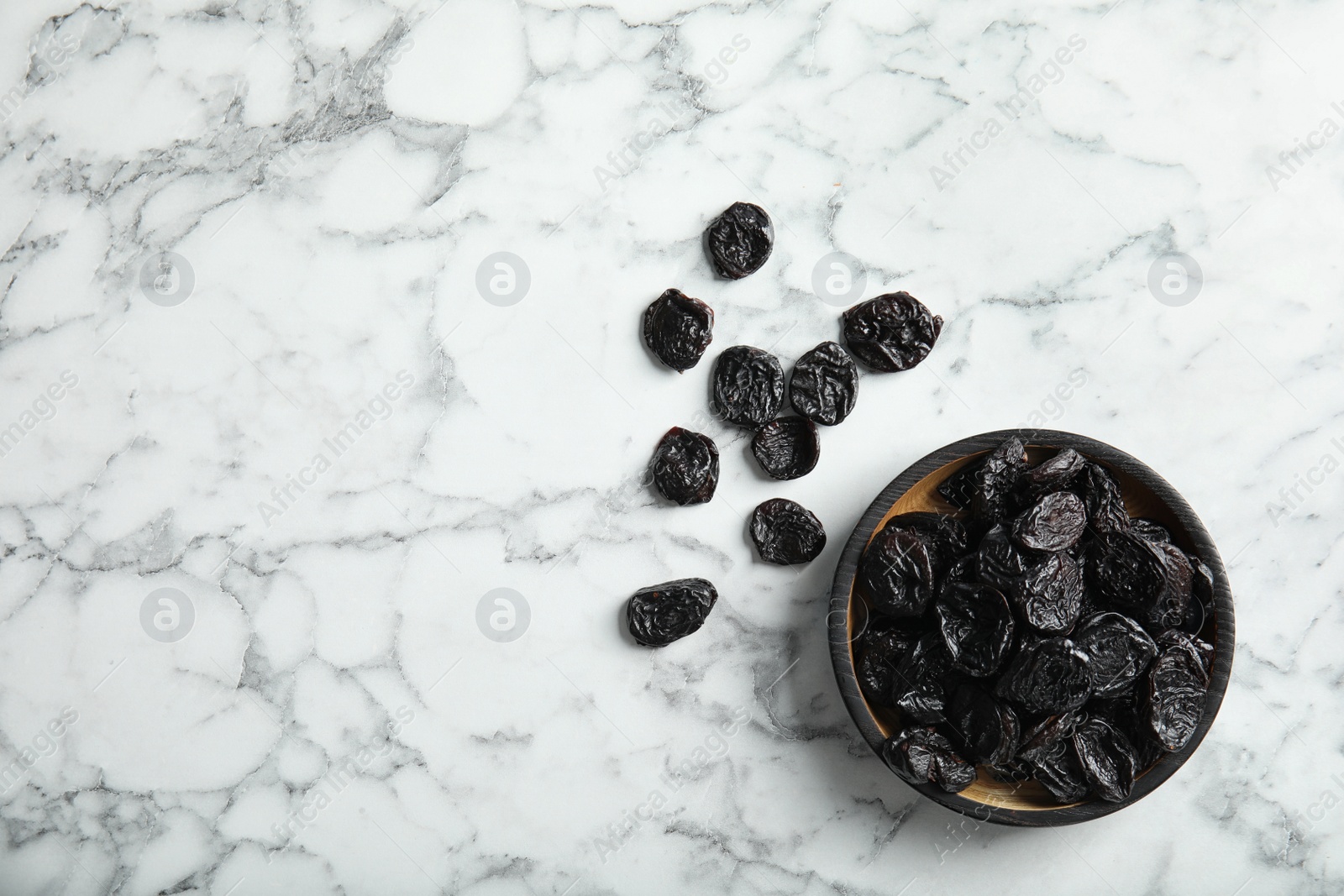 Photo of Plate of sweet dried plums on marble background, top view with space for text. Healthy fruit