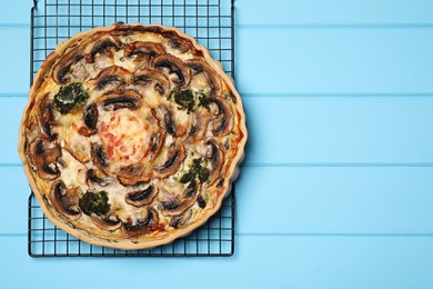 Photo of Delicious quiche with mushrooms on light blue wooden table, top view. Space for text