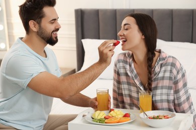 Photo of Happy couple having breakfast on bed at home