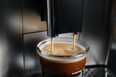 Photo of Espresso machine pouring coffee into glass, closeup