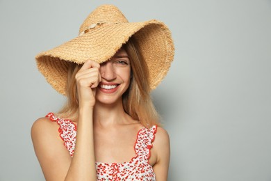 Photo of Beautiful young woman wearing straw hat on light grey background, space for text. Stylish headdress