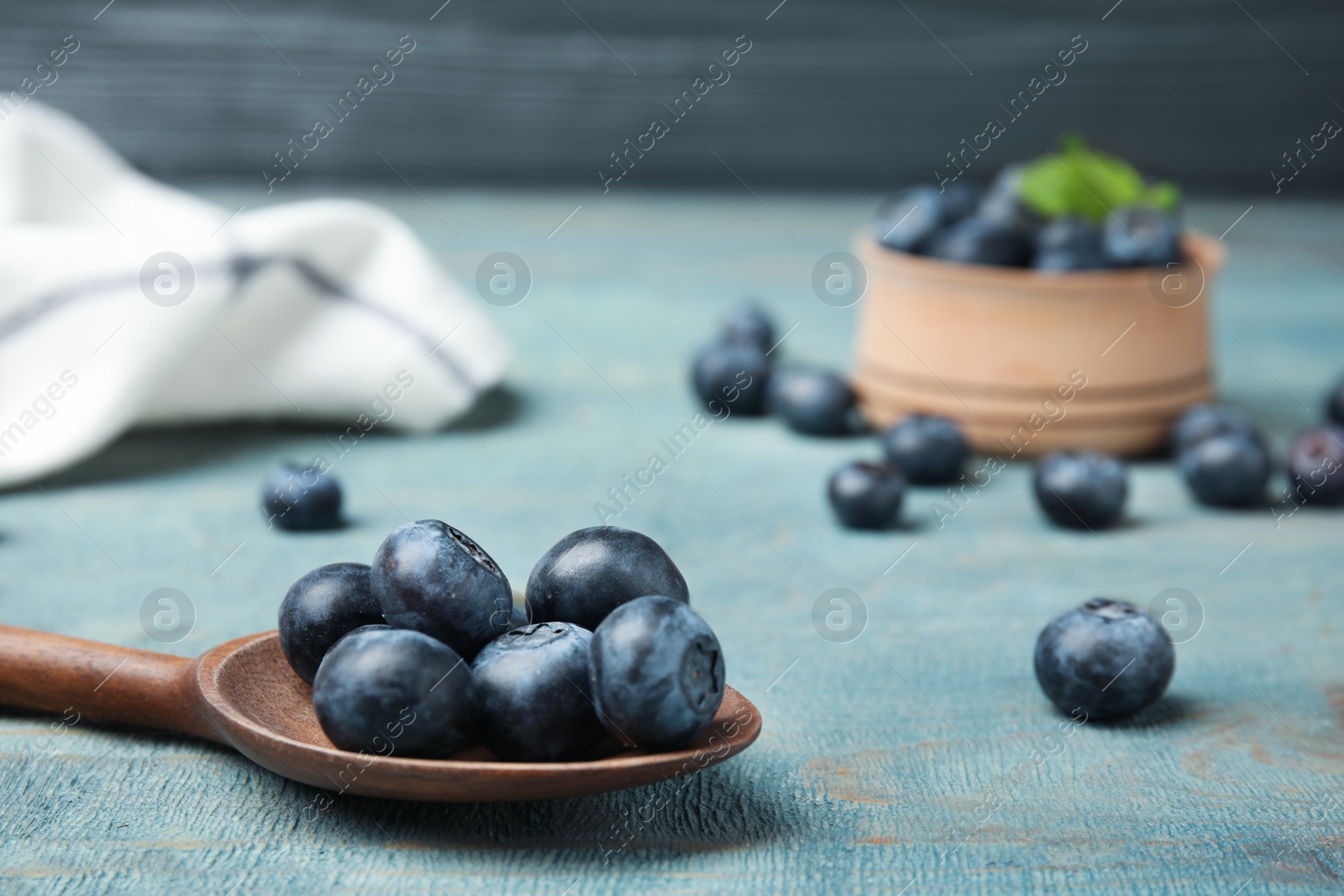 Photo of Spoon with tasty blueberries on wooden table, closeup. Space for text