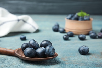 Photo of Spoon with tasty blueberries on wooden table, closeup. Space for text