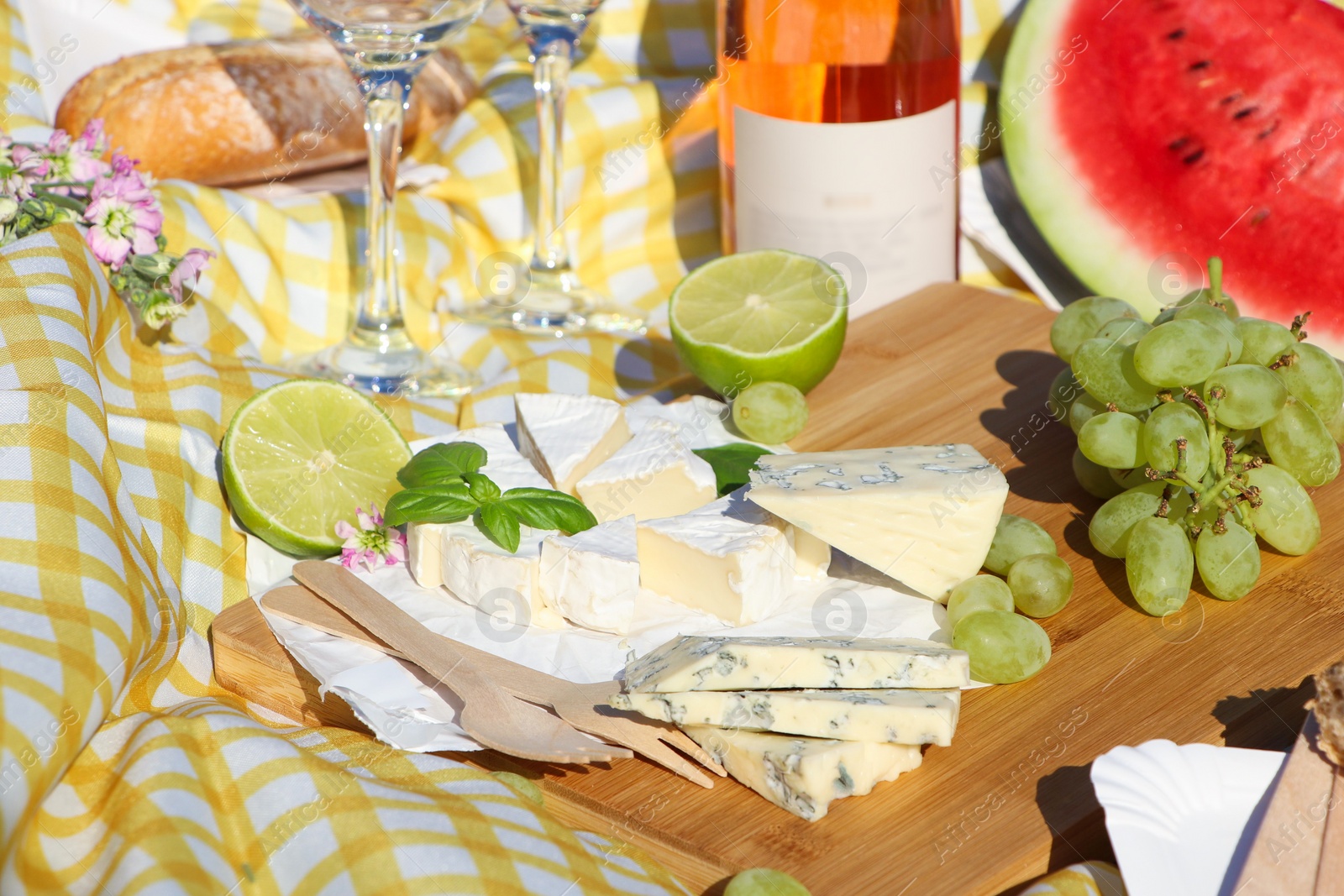 Photo of Delicious food and wine on picnic blanket, closeup