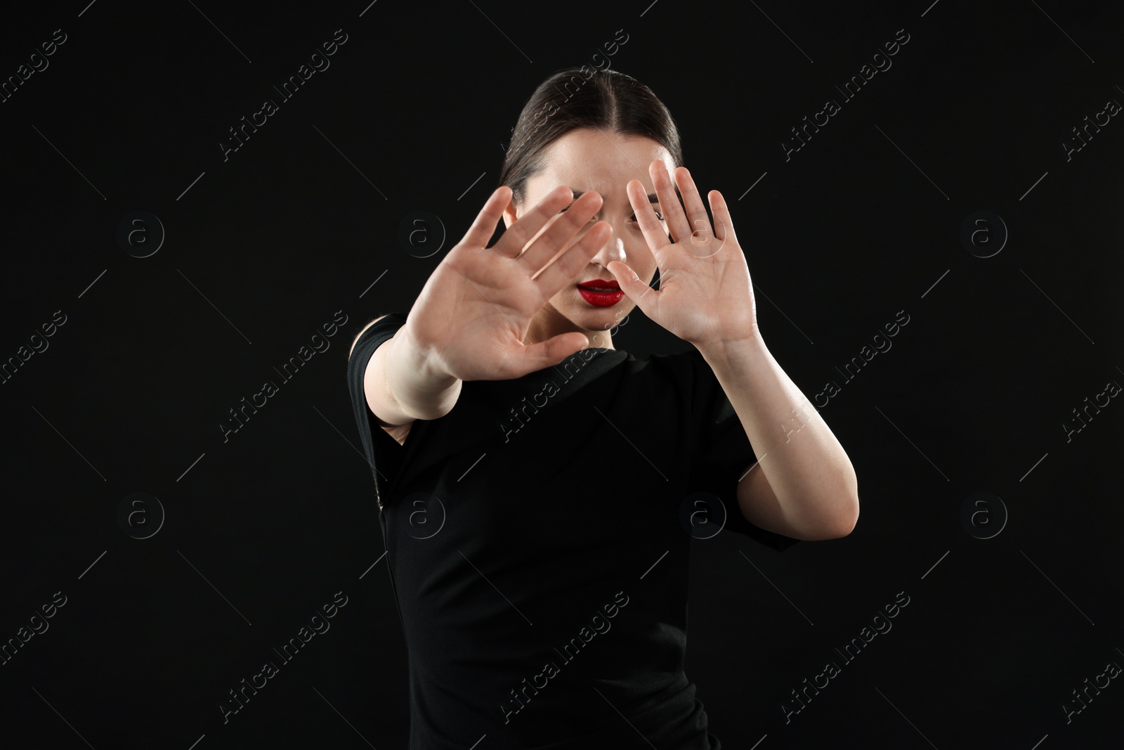 Photo of Beautiful woman covering face with hands on black background