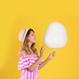 Photo of Happy young woman with cotton candy on yellow background