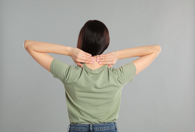 Woman suffering from pain in neck on light grey background. Visiting orthopedist