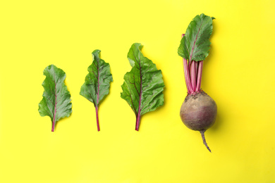 Photo of Whole fresh red beet and leaves on yellow background, flat lay