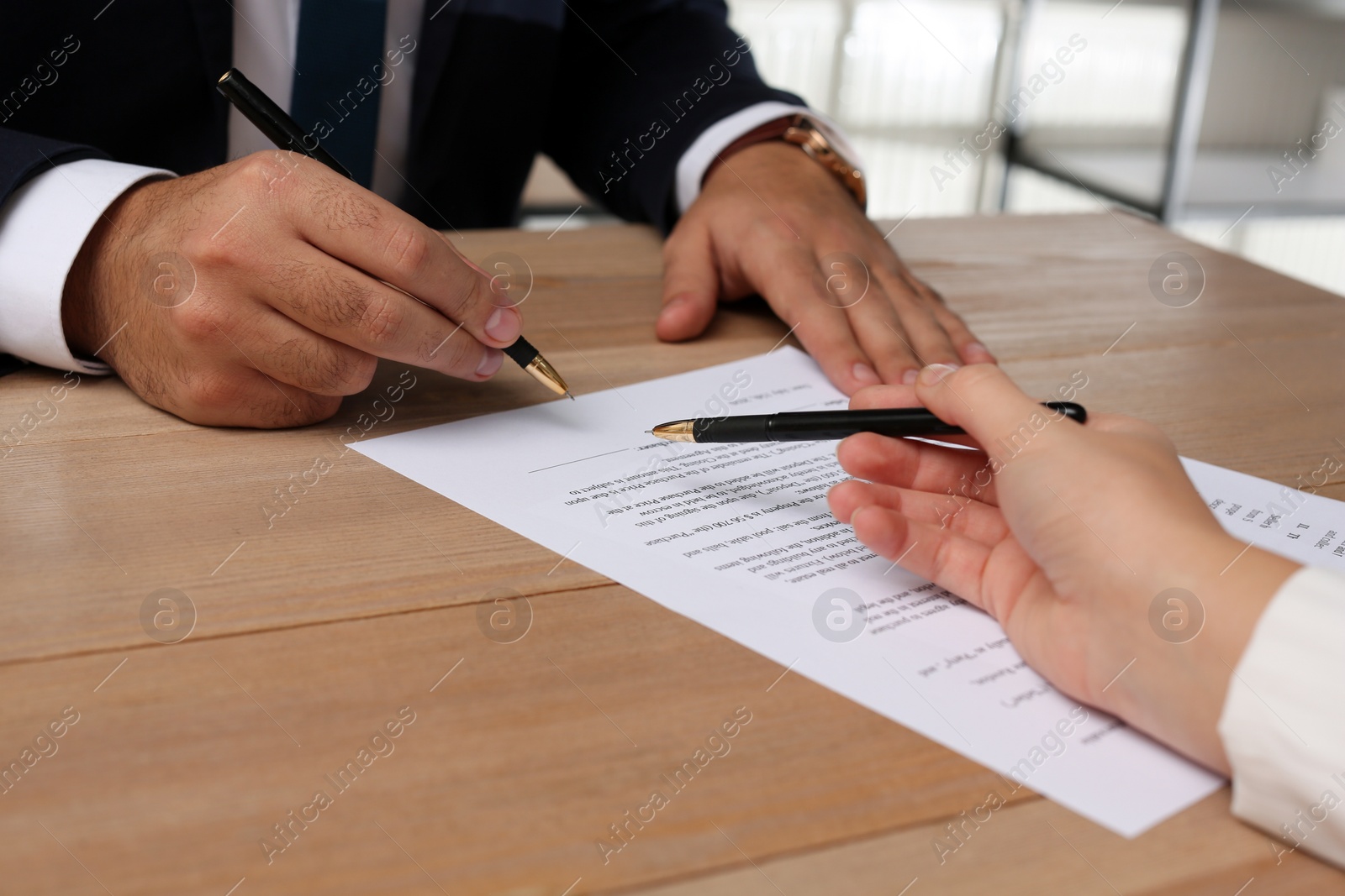 Photo of Businesspeople working with contract at wooden table indoors, closeup