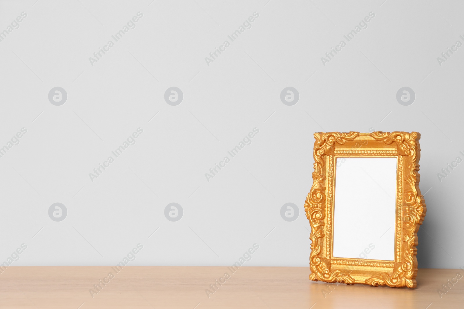 Photo of Beautiful golden vintage frame on wooden table, space for text