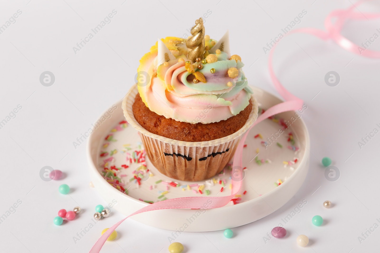 Photo of Cute sweet unicorn cupcake on white table