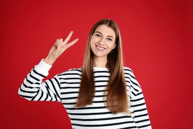 Woman showing number two with her hand on red background