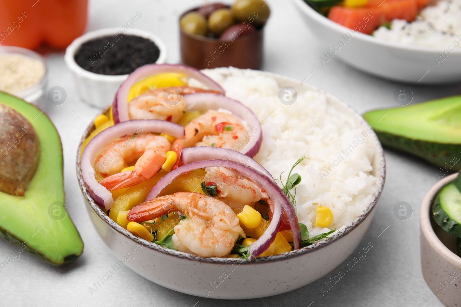 Photo of Poke bowl and ingredients on white table, closeup