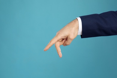 Photo of Businessman imitating walk with hand on light blue background, closeup. Finger gesture