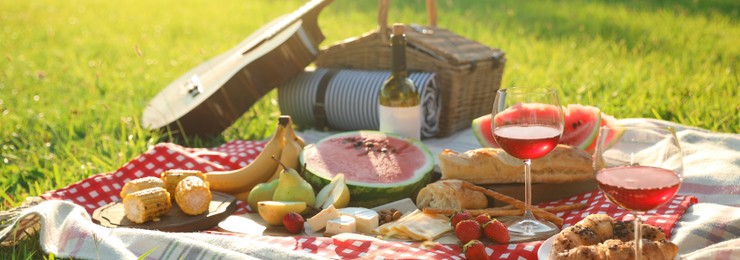 Image of Picnic blanket with delicious food and drinks outdoors on sunny day. Banner design