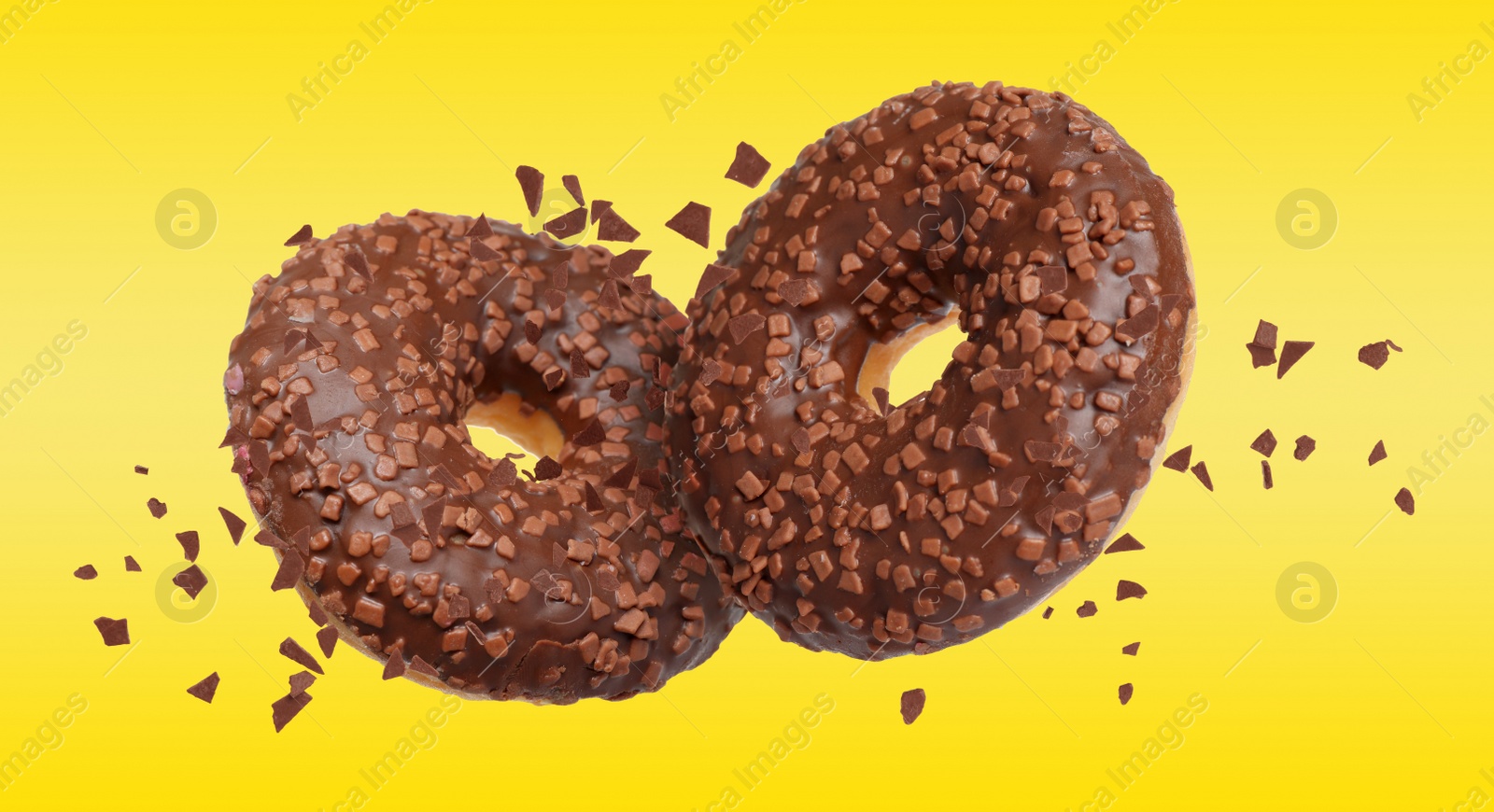 Image of Sweet delicious donuts falling on yellow background
