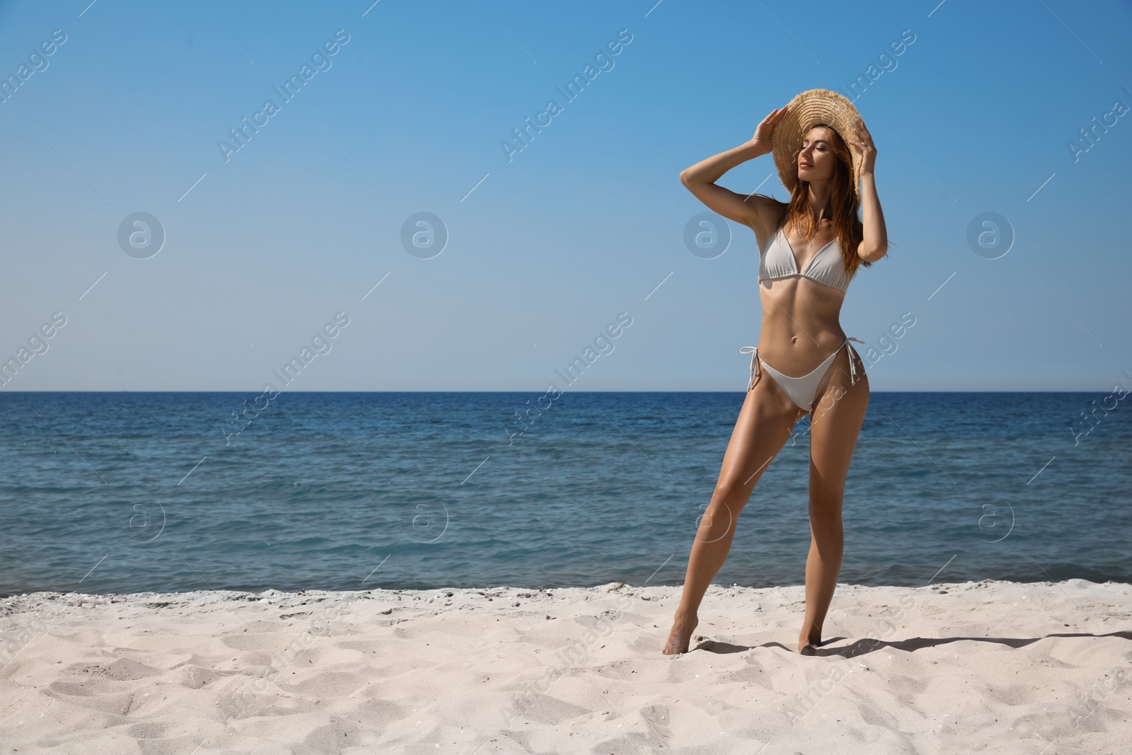Photo of Attractive woman in bikini on sandy beach near sea