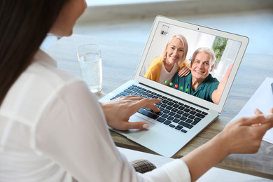 Image of Young woman having video chat with her grandparents at home, focus on screen