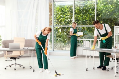 Team of janitors in uniform cleaning office