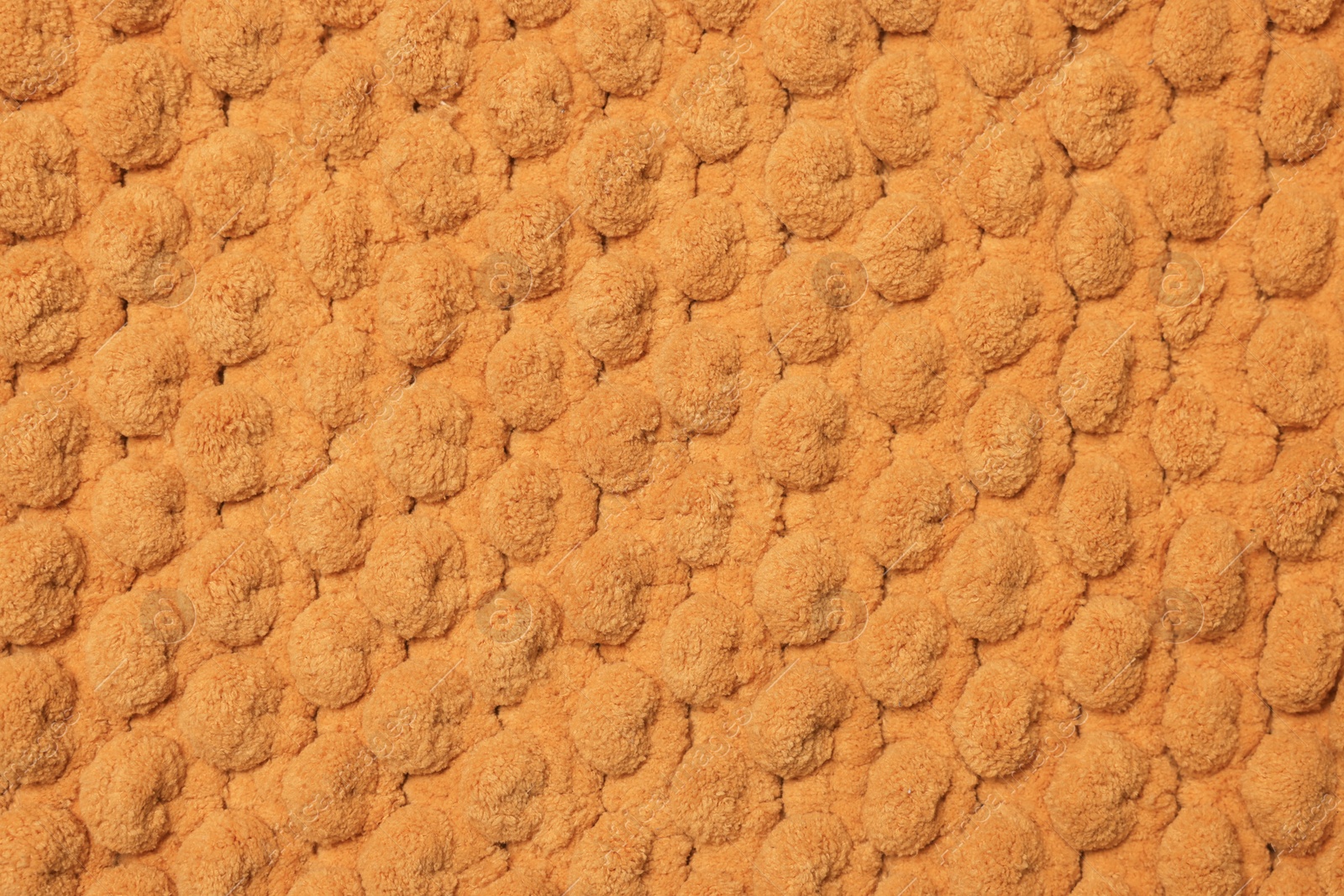 Photo of Soft orange bath mat as background, top view