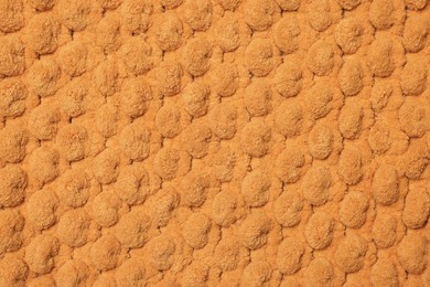 Soft orange bath mat as background, top view