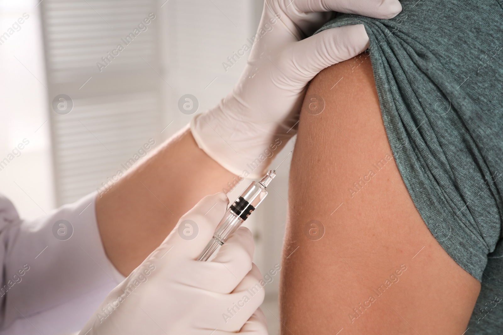 Photo of Doctor vaccinating man against Covid-19 in clinic, closeup