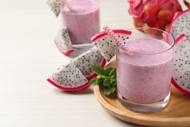 Photo of Delicious pitahaya smoothie, mint and fresh fruits on white wooden table, space for text